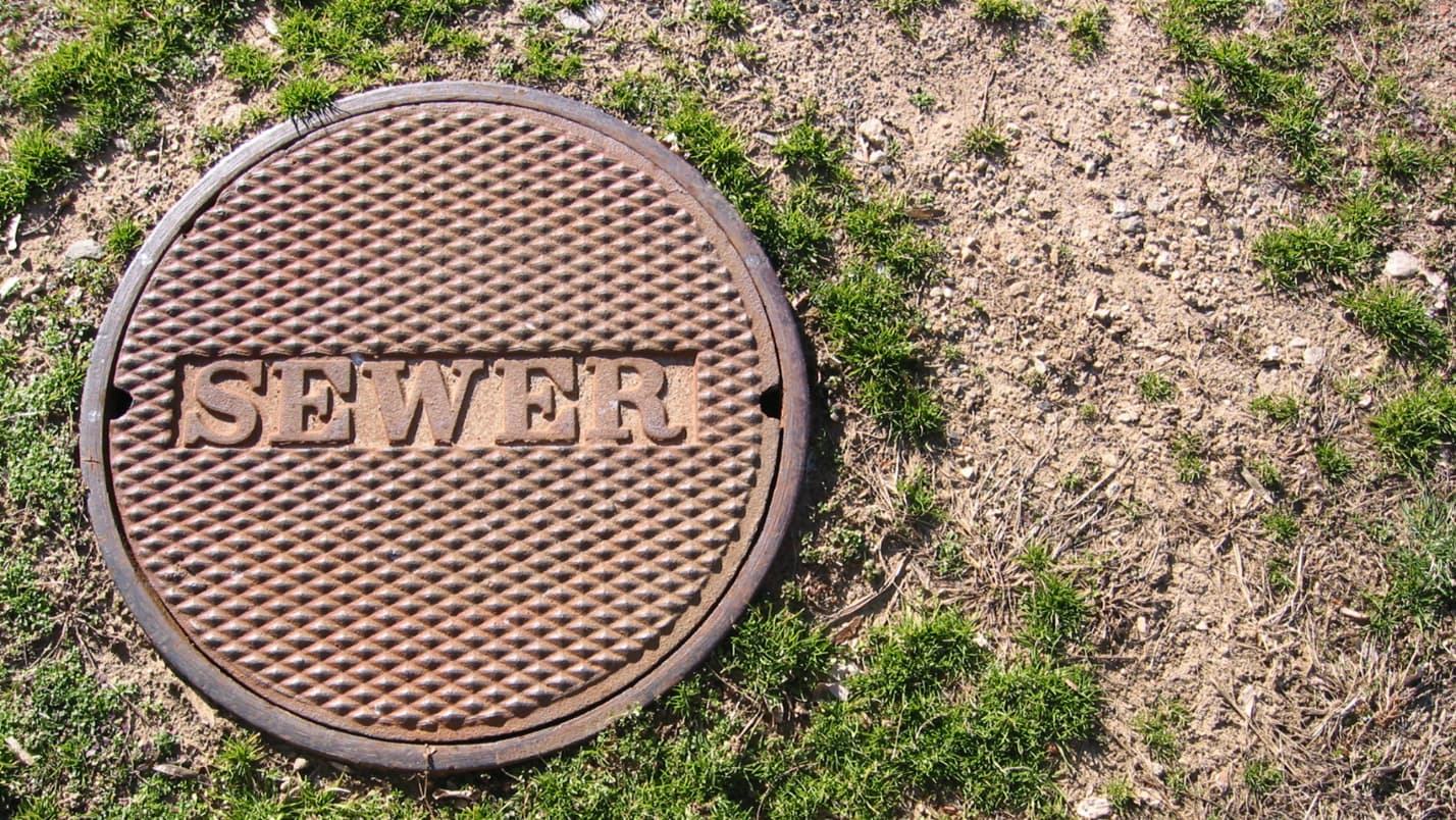 A manhole cover with the word “sewer” stamped on it.